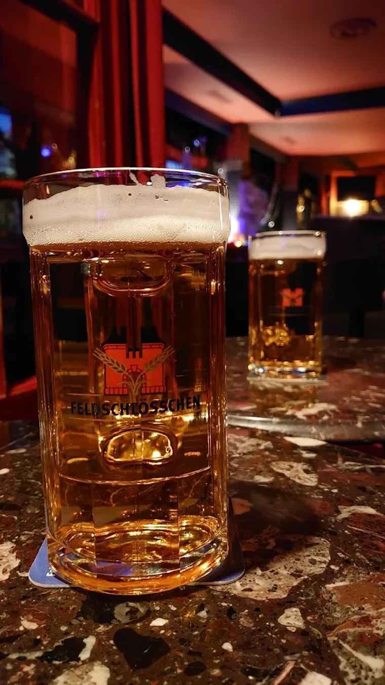 Chope de bière Feldschlösschen bien fraîche posée sur une table en marbre du Pub Lord Jim.