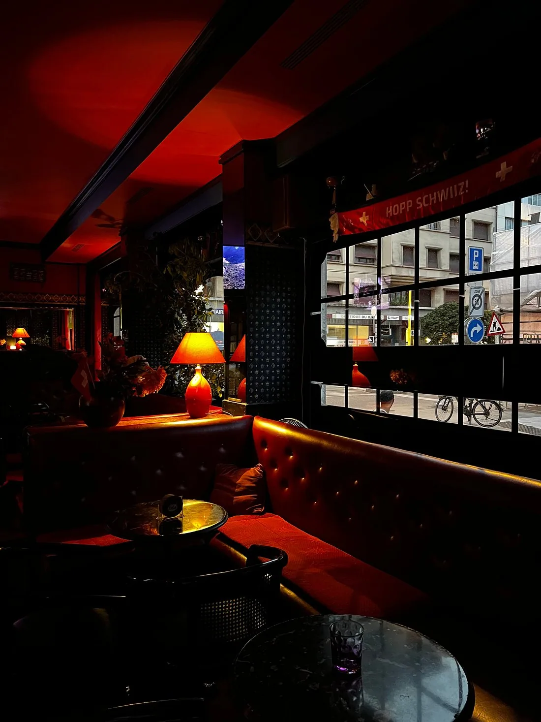 Banquettes chesterfield et lampes en laiton du Pub Lord Jim, fanion suisse à la fenêtre.